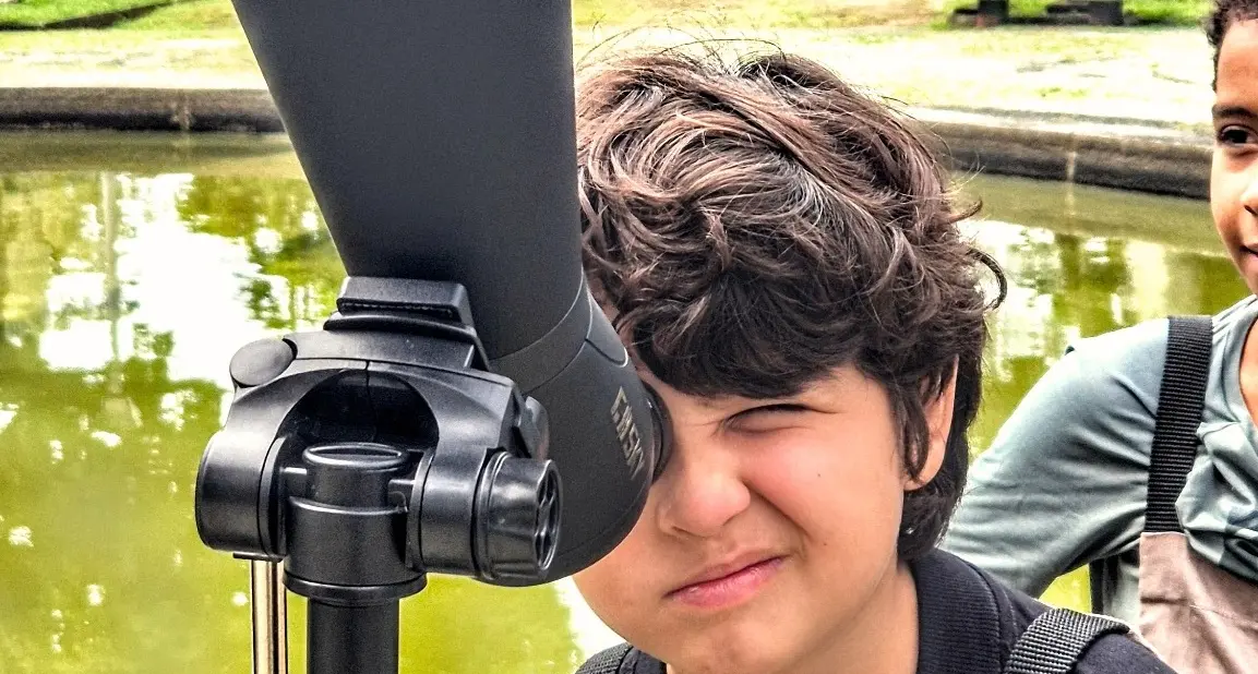 Menino observando aves por uma luneta durante o Vem Passarinhar Recife